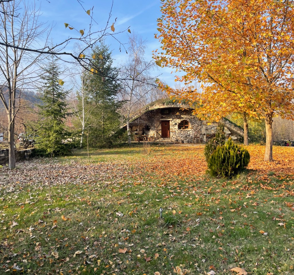 A house that looks like a hobbit home. It has grass-covered roof and is made of stone.
